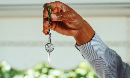 person holding key Why Renting Apartments in Carrollton, TX Beats Buying at EVIVA at Trinity Mills Station